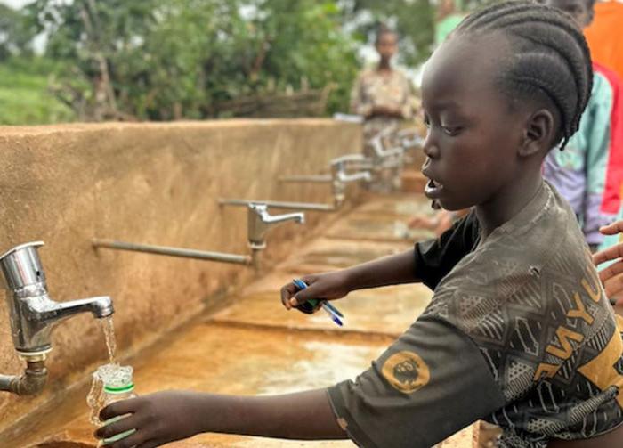 A child fills up a water bottle with clean water thanks the World Vision program